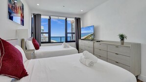 Een hotelkamer met twee bedden, een groot raam met uitzicht, een televisie en een dressoir.