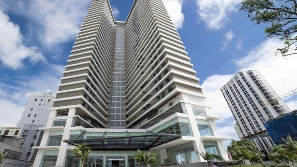 A modern high-rise hotel with a distinctive V-shaped facade, multiple balconies, and a covered entrance area. - Dan - FLC Sea Tower Quy Nhon (Quy Nhon Nam)