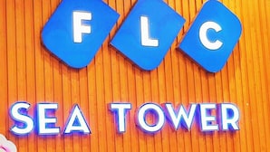 A sign with the letters "FLC" and the words "SEA TOWER" on a wooden background. - Dan - FLC Sea Tower Quy Nhon (Quy Nhon Nam)