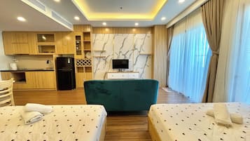A hotel room with two beds, a kitchenette, a TV, and a marble wall.