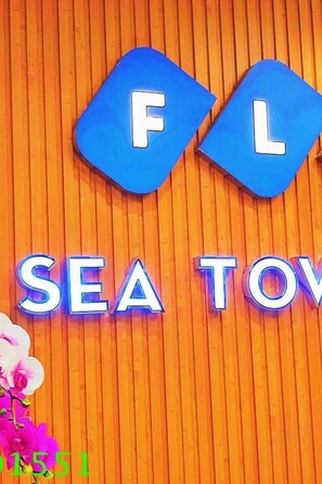 Un letrero con las letras "FLC" y las palabras "SEA TOWER" sobre un fondo de madera.