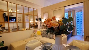 A modern living room with a dining area set for a meal. - Fourth's Jazz Cozy Pad (Makati)