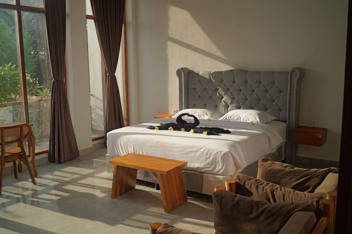 Un dormitorio con una cama grande, un banco de madera y una pequeña mesa.