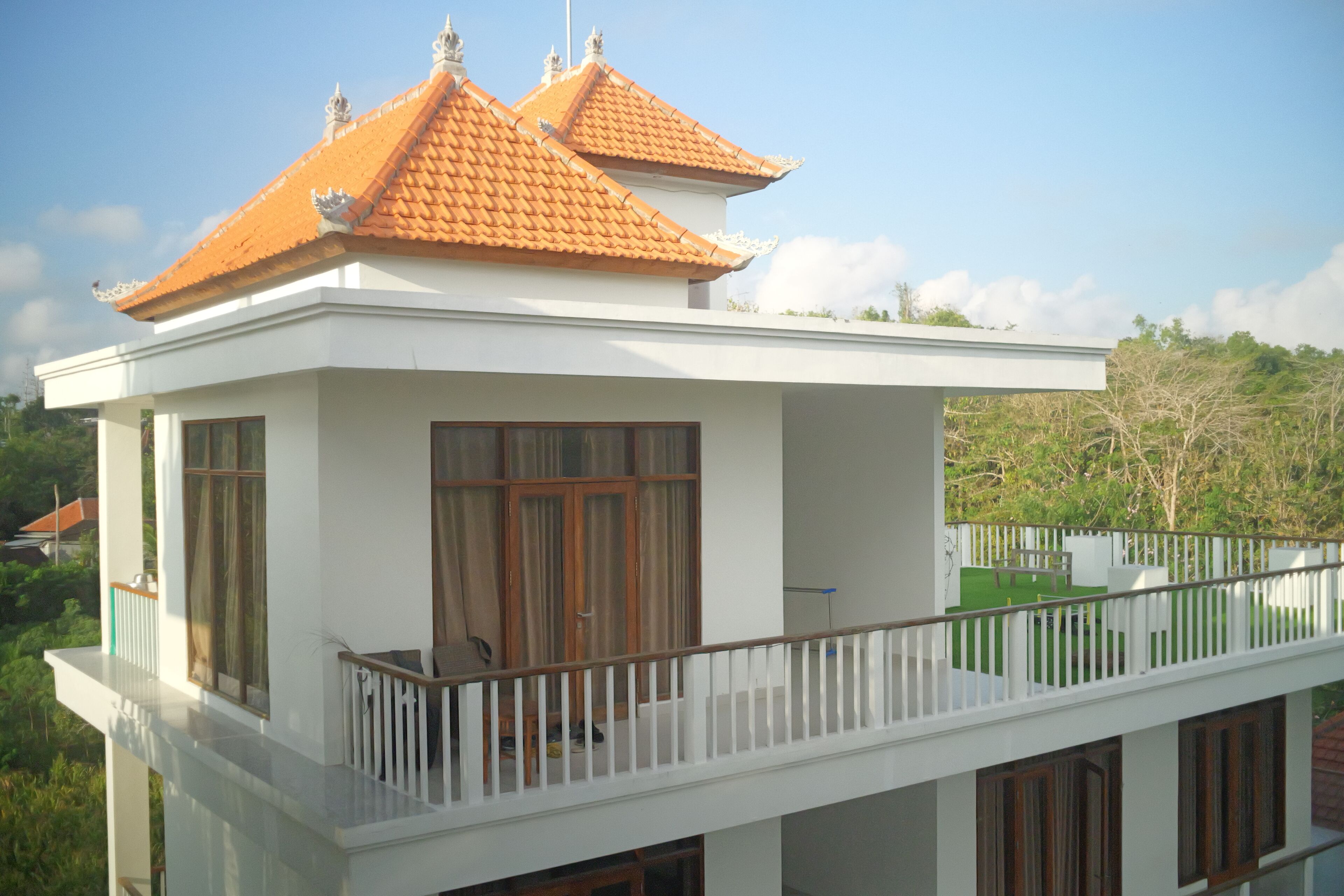 Un bâtiment à deux étages, avec une façade blanche et un toit recouvert de tuiles orange.