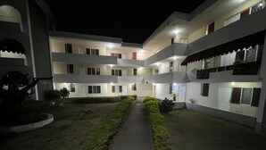 A multi-story hotel with a central courtyard, well-lit pathways, and neatly trimmed hedges. - The Central Comfort in Kingston (Kingston)