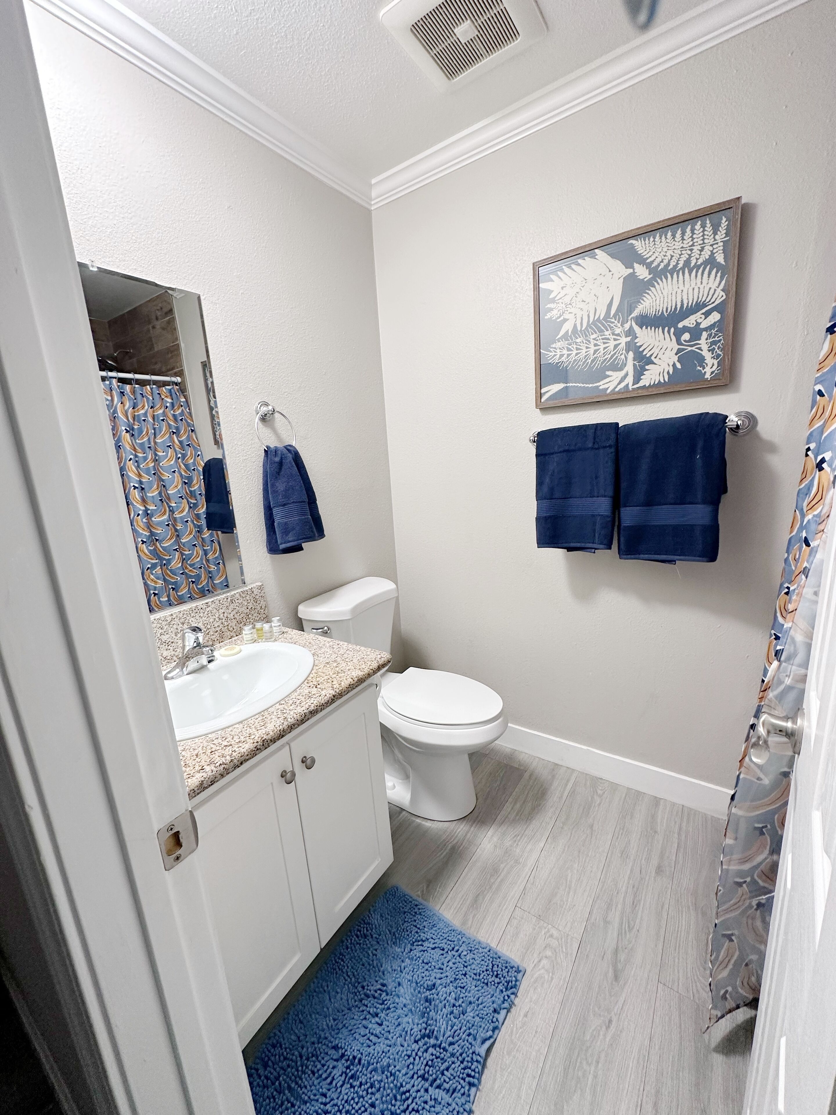 Un baño con lavamanos blanco, inodoro y cortina de ducha azul.
