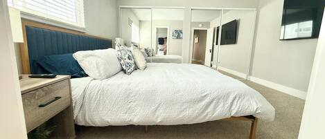 A bedroom with a bed, bedside table, and a nightstand.