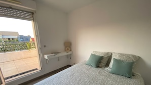 Ein Schlafzimmer mit Bett, Nachttisch, Lampe und Fenster.