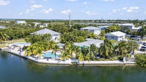 Un quartier résidentiel situé sur la côte, avec des maisons, une piscine et des palmiers.