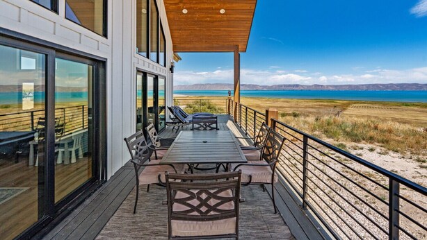 Eine Terrasse mit Tisch und Stühlen mit Blick auf Strand und Berge.