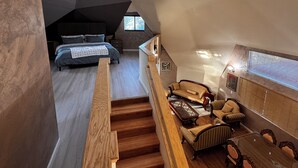 Ein großzügiges Schlafzimmer im Loft-Stil mit schrägem Dach, Oberlichtern, einem großen Bett und Blick auf den angrenzenden Wohnbereich.