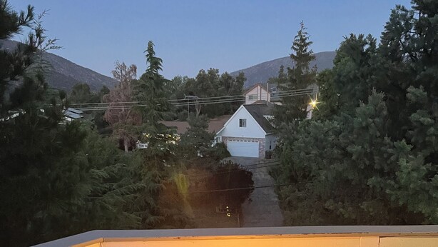 Ein rechteckiges Feuerbecken im Freien mit Flammen, umgeben von einer Holzterrasse mit weißen Geländern.