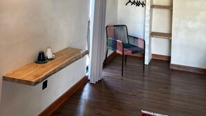 Une pièce avec un banc en bois, un climatiseur fixé au mur, un ventilateur de plafond, un porte-manteau suspendu et un placard entrouvert.