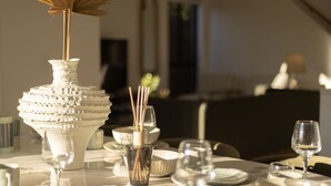 A dining table set with white plates, bowls, and a decorative vase with a tall stem and a fan-like top. - Spacious 5BR Home in Heart of Sunnybank |Sleeps 10 (Sunnybank)