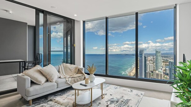 A modern living room with a large window offering a city and ocean view.