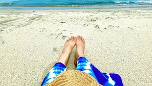 Una spiaggia con cielo sereno, mare calmo e isole all'orizzonte.