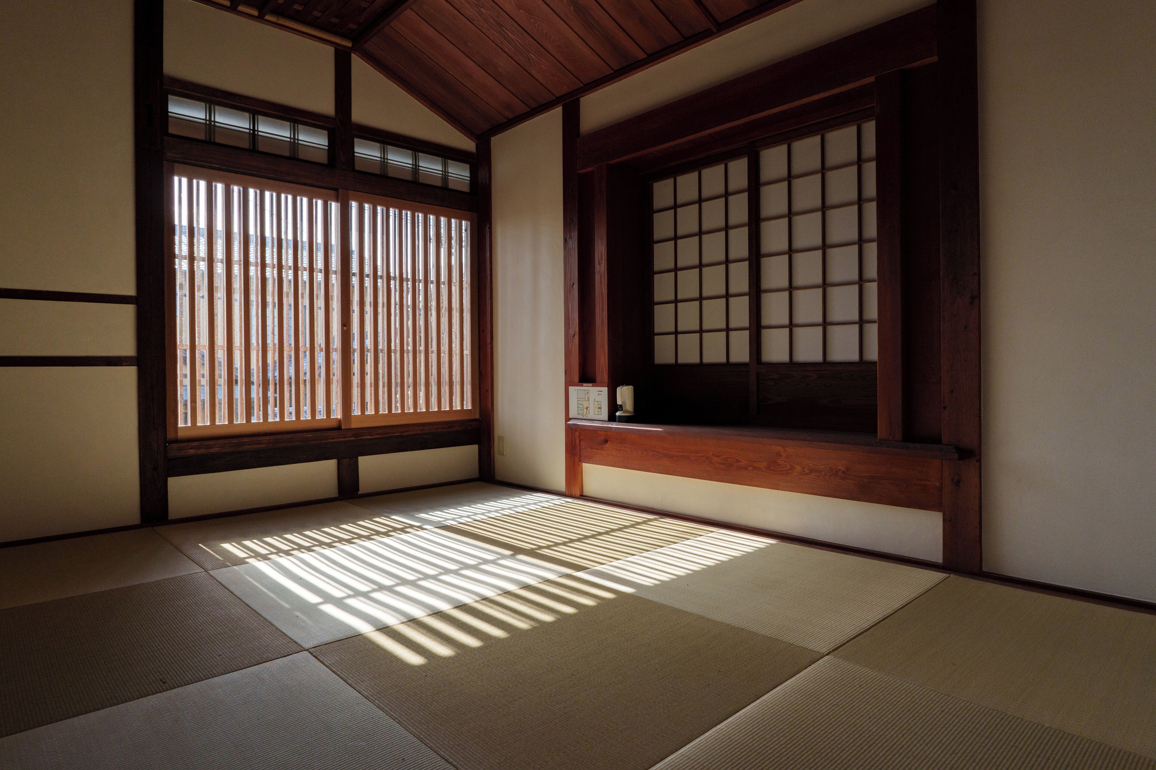 A traditional Japanese room with tatami flooring, sliding doors, and a wooden beam ceiling.