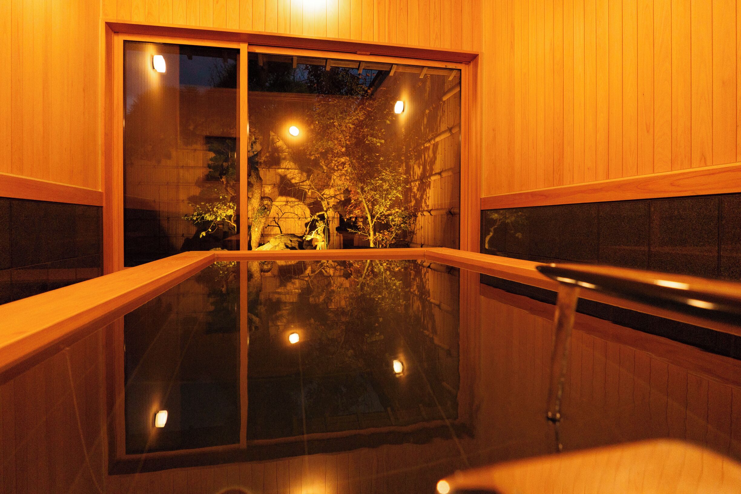 A room with a large glass window, wooden walls, and a wooden floor.