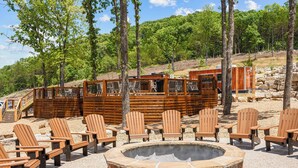 A wooden deck with Adirondack chairs, a stone fire pit, and a wooden building with a covered area. - Ledgerock Cabin – Elegant 3BR Retreat in Tall Timbers Resort (Hollister)