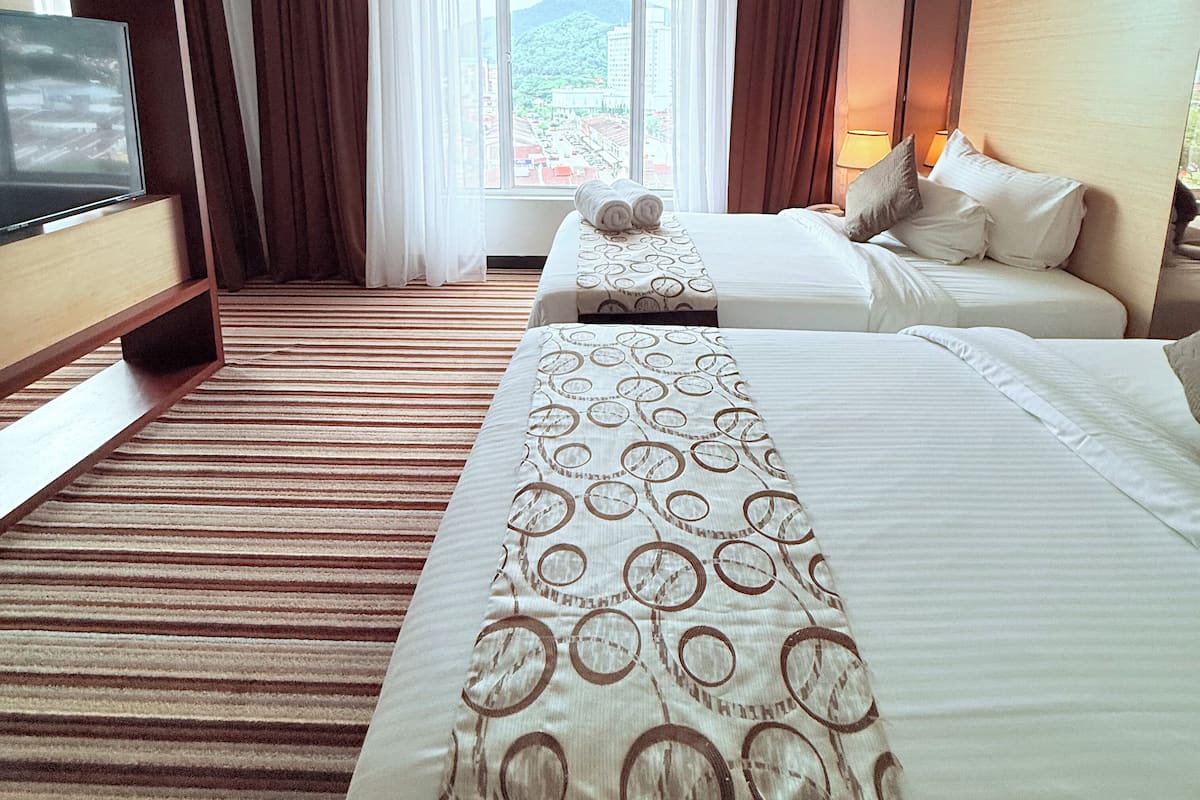 Una habitación de hotel con dos camas, televisión y vistas a la ciudad.