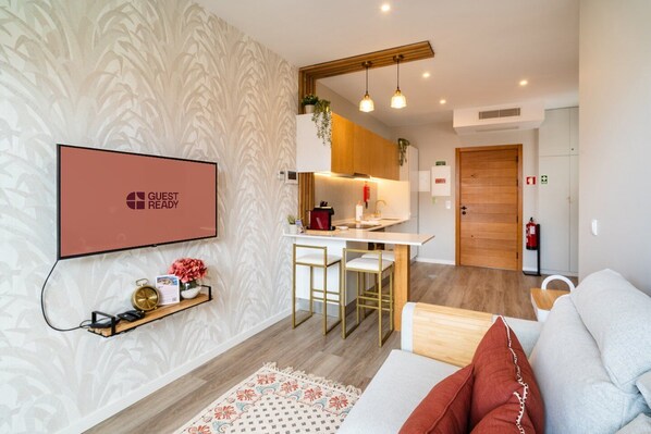 Een moderne keuken met een wit aanrecht, barstoelen en een houten deur.