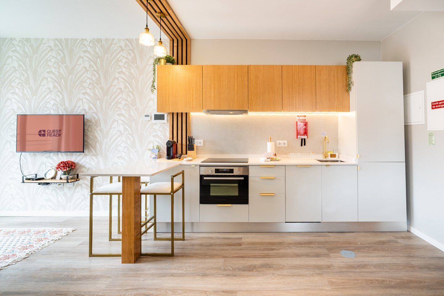 Eine moderne Küche mit weißen Schränken, einem eingebauten Backofen und einem Essbereich mit weißem Tisch und zwei Stühlen.