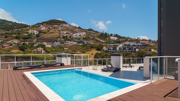 Una piscina sul tetto con vista su una cittadina collinare.