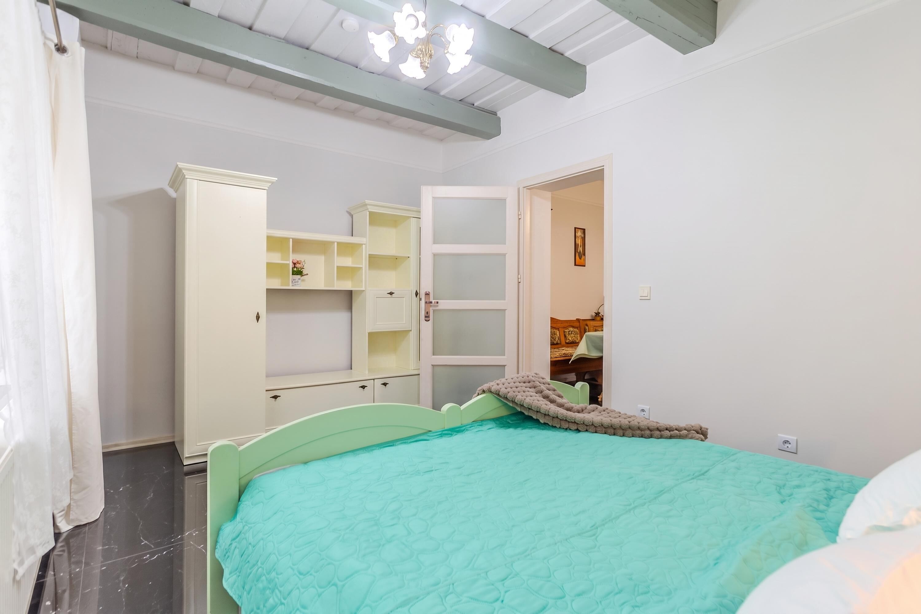 A bedroom with a bed, a wardrobe, and a door leading to another room.