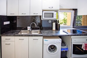 Eine kompakte Küche mit integriertem Mikrowellenherd, Spülbecken aus Edelstahl und Waschmaschine.