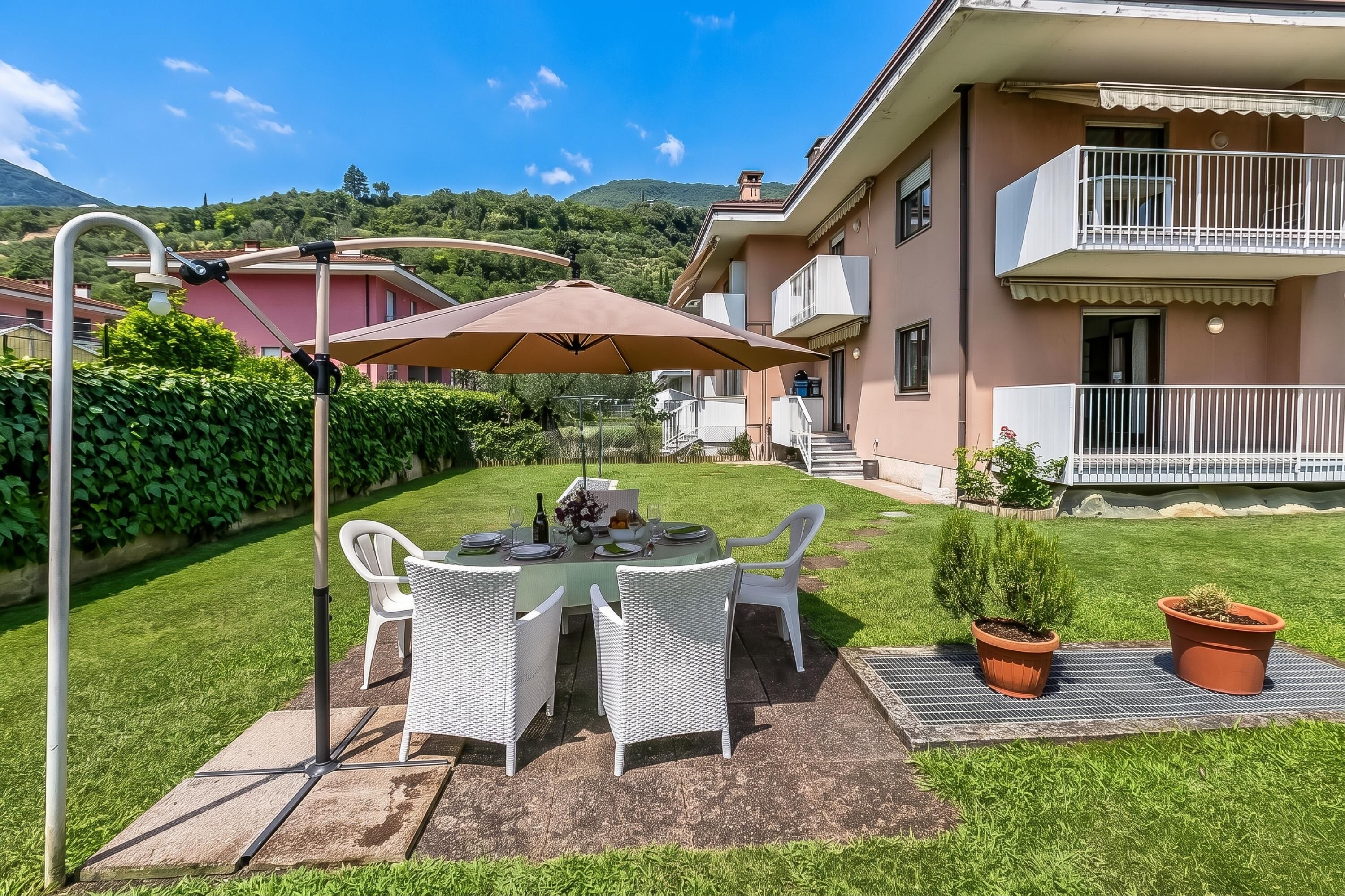 A patio with a table and chairs, a pergola, and a view of a residential building with a balcony.