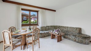 A dining area with a round table, chairs, and a sofa. - The Olive Tree Garden With Mountain View (Arco)