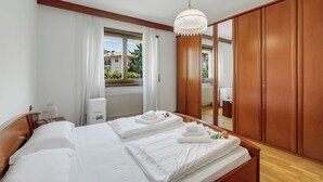 A hotel room with a large bed, wooden wardrobe, and a window with curtains. - The Olive Tree Garden With Mountain View (Arco)