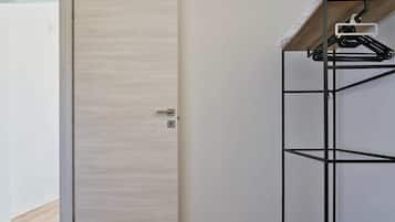 Een kamer met een houten deur, een zwart metalen rek en een airconditioner aan de muur.