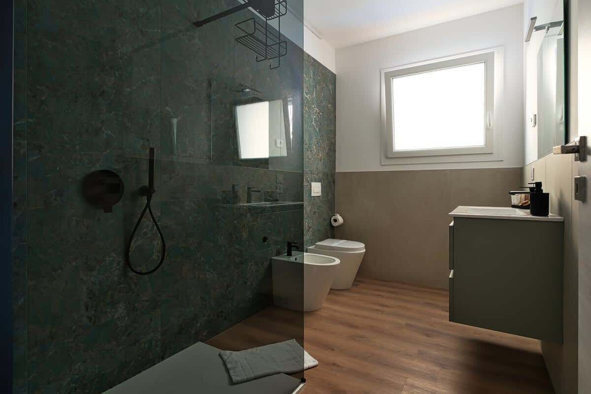 Un baño moderno con cabina de ducha de vidrio, inodoro y tocador con espejo.