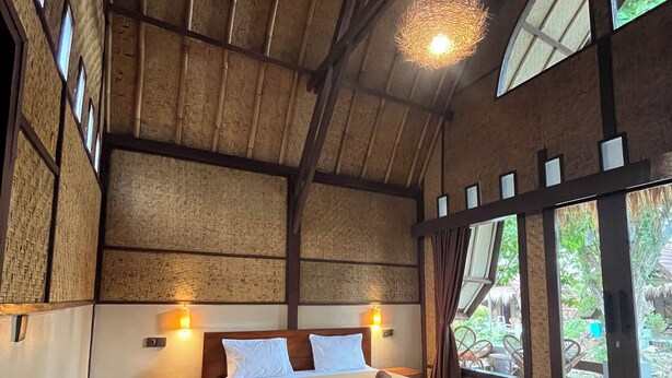 A spacious bedroom with a large bed, wooden beams, and large windows. - Gila House (Gili Air)
