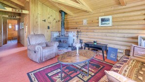 Ein Holzblockhaus-Interieur mit Kamin, Ledersessel und rundem Tisch.