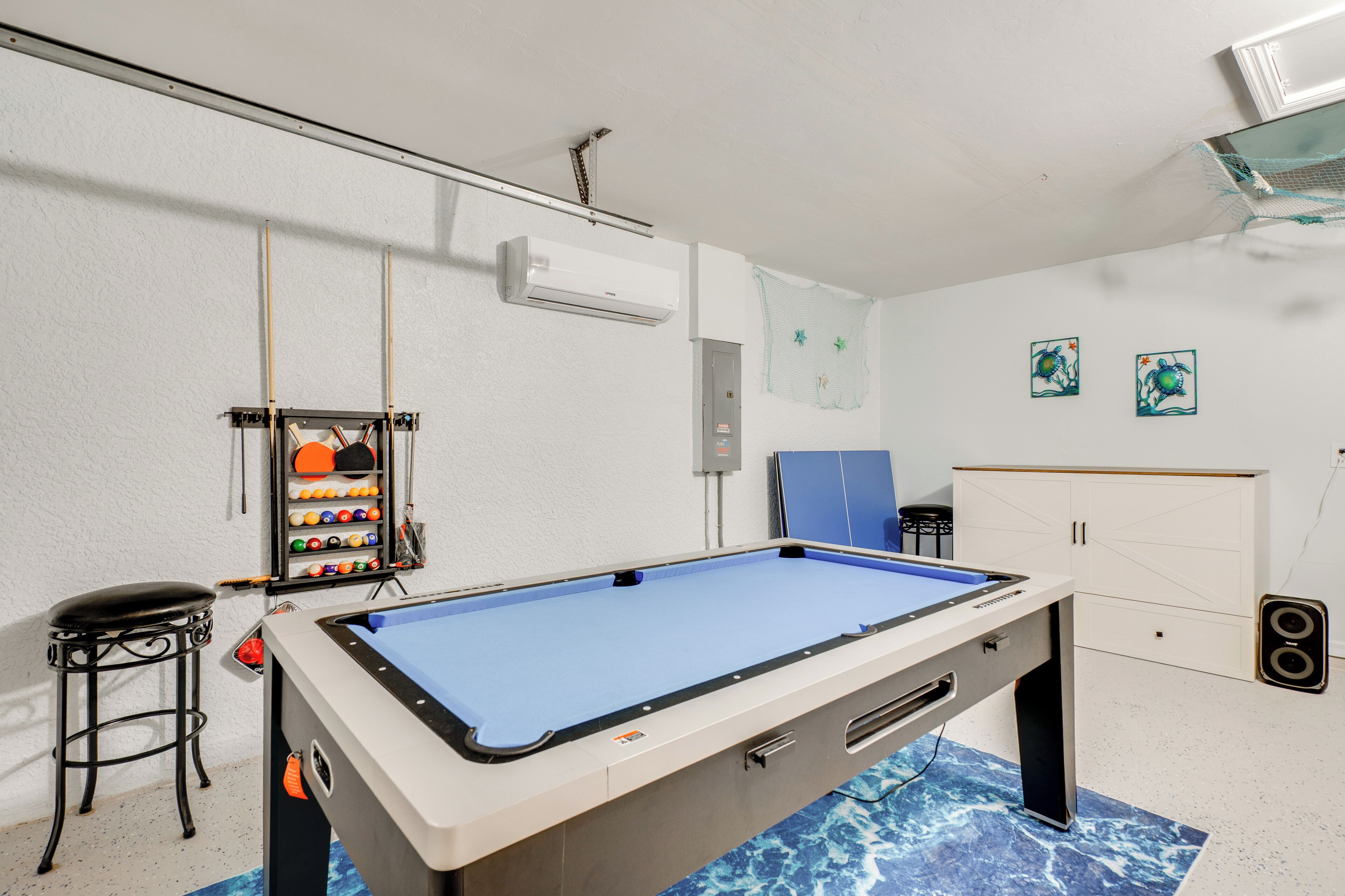 Ein Billardtisch mit blauer Spielbahn, ein Billardständer und ein Hocker.