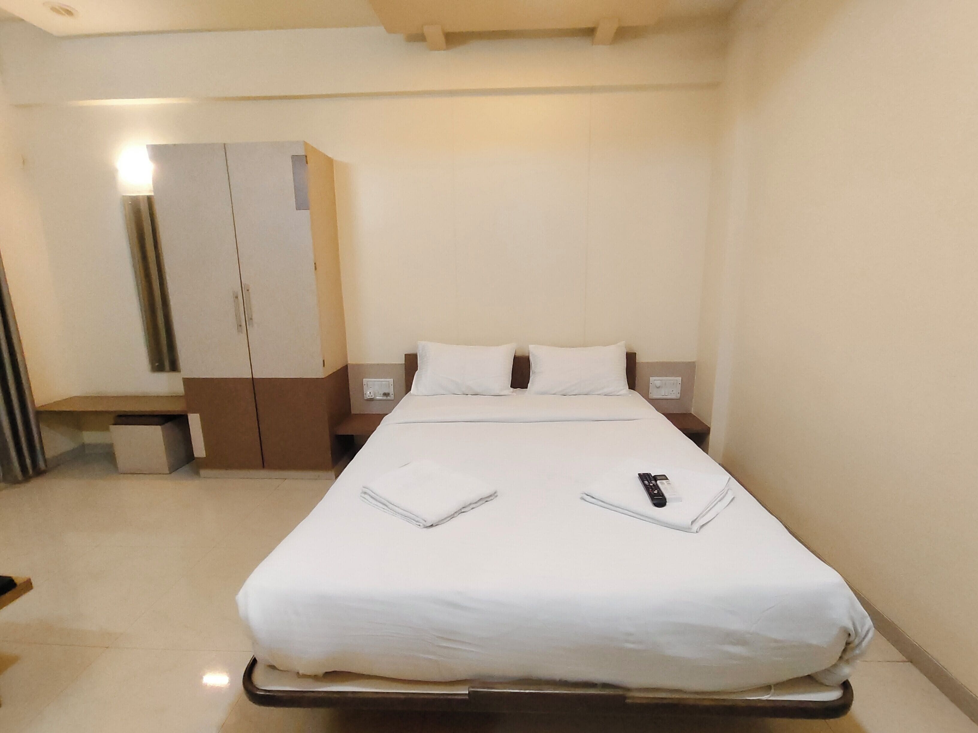 Een hotelkamer met een bed, een kledingkast en een nachtkastje.