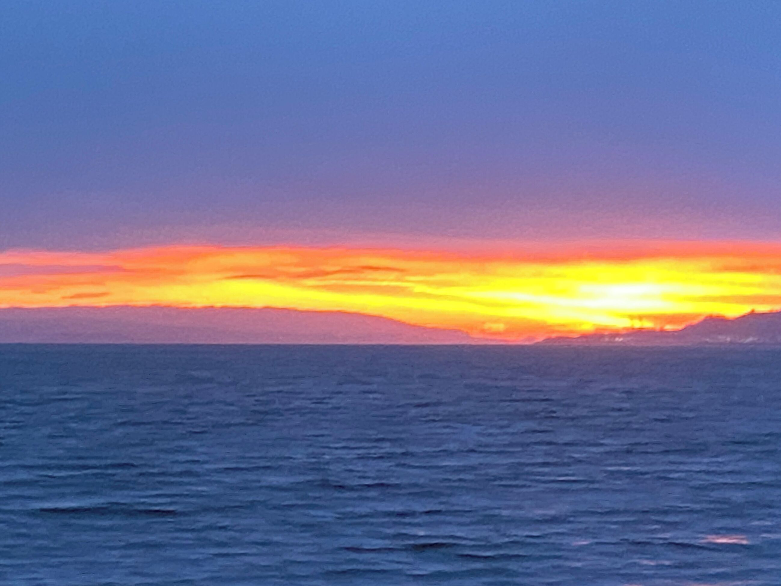 Solnedgang over havet med roligt vand.