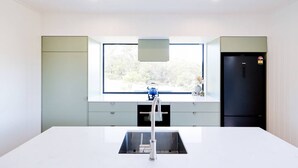 Eine moderne Küche mit einem großen Fenster, einer eingebauten Spüle und einem schwarzen Kühlschrank.