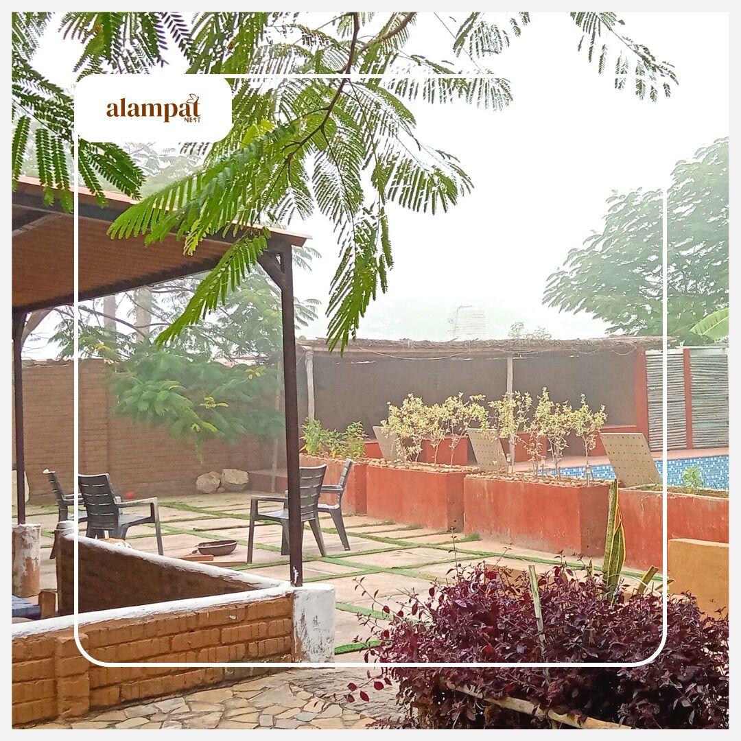An outdoor patio area with a pergola, potted plants, and a seating arrangement.