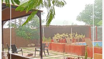 An outdoor patio area with a pergola, potted plants, and a seating arrangement.