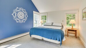 Ein Schlafzimmer mit einem Bett, zwei Fenstern, einem Nachttisch und einer Wanddekoration.