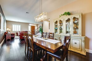 Un coin repas avec une table et des chaises en bois, un lustre et un buffet.