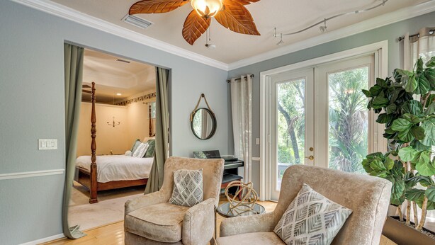 A spacious room with a large bed, two armchairs, a small table, and a large window with a view of greenery. - Forested Wimauma Retreat 2 Mi to State Park! (Wimauma)