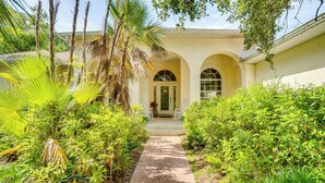 A pathway leading to a building with arched windows and a door, surrounded by lush greenery and a palm tree. - Forested Wimauma Retreat 2 Mi to State Park! (Wimauma)