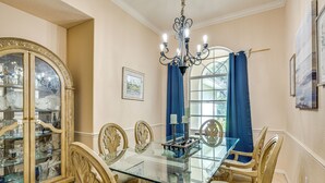 A dining room with a glass table, ornate chairs, a chandelier, and a cabinet with glass doors. - Forested Wimauma Retreat 2 Mi to State Park! (Wimauma)