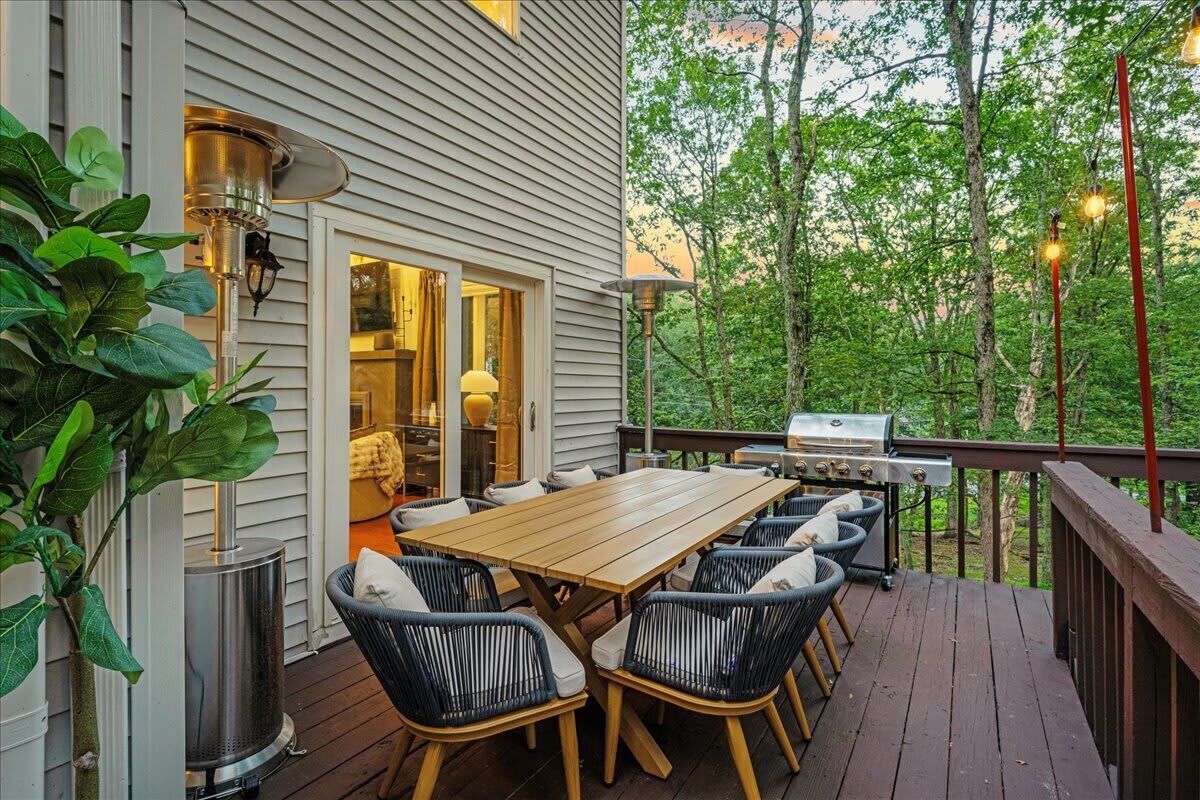 A deck with a wooden table and chairs, a grill, and a potted plant.