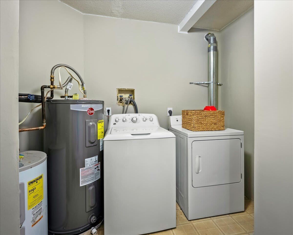 Une buanderie équipée d’un chauffe-eau, d’un lave-linge et d’un sèche-linge.