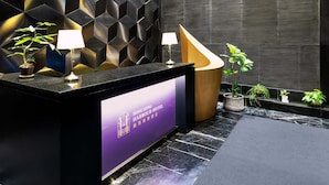A reception desk with a modern design, featuring a black and purple color scheme, a digital display, and potted plants. - Hong Kong Harbour Hotel (Hong Kong Island)